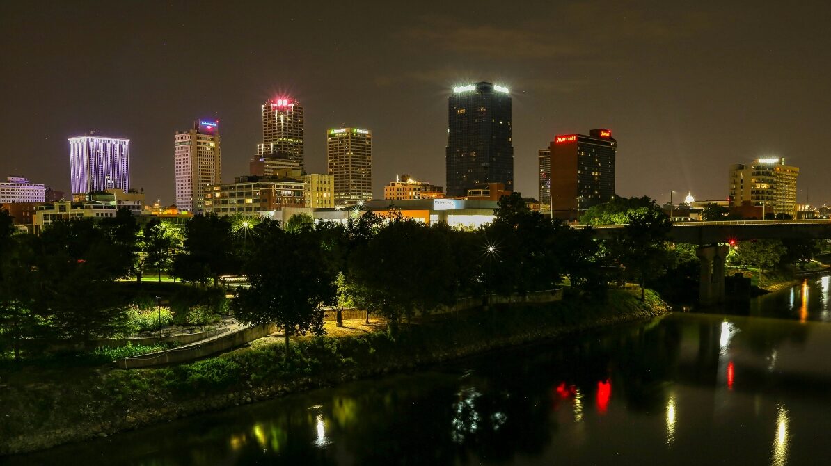 Little Rock, Arkansas skyline at night with illuminated buildings and reflections along the Arkansas River