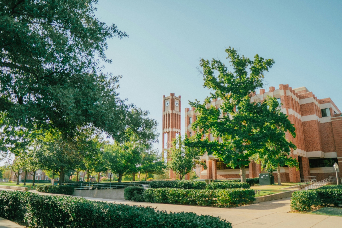 University of Oklahoma campus in Norman with a brick academic building and clock tower surrounded by trees and walkways
