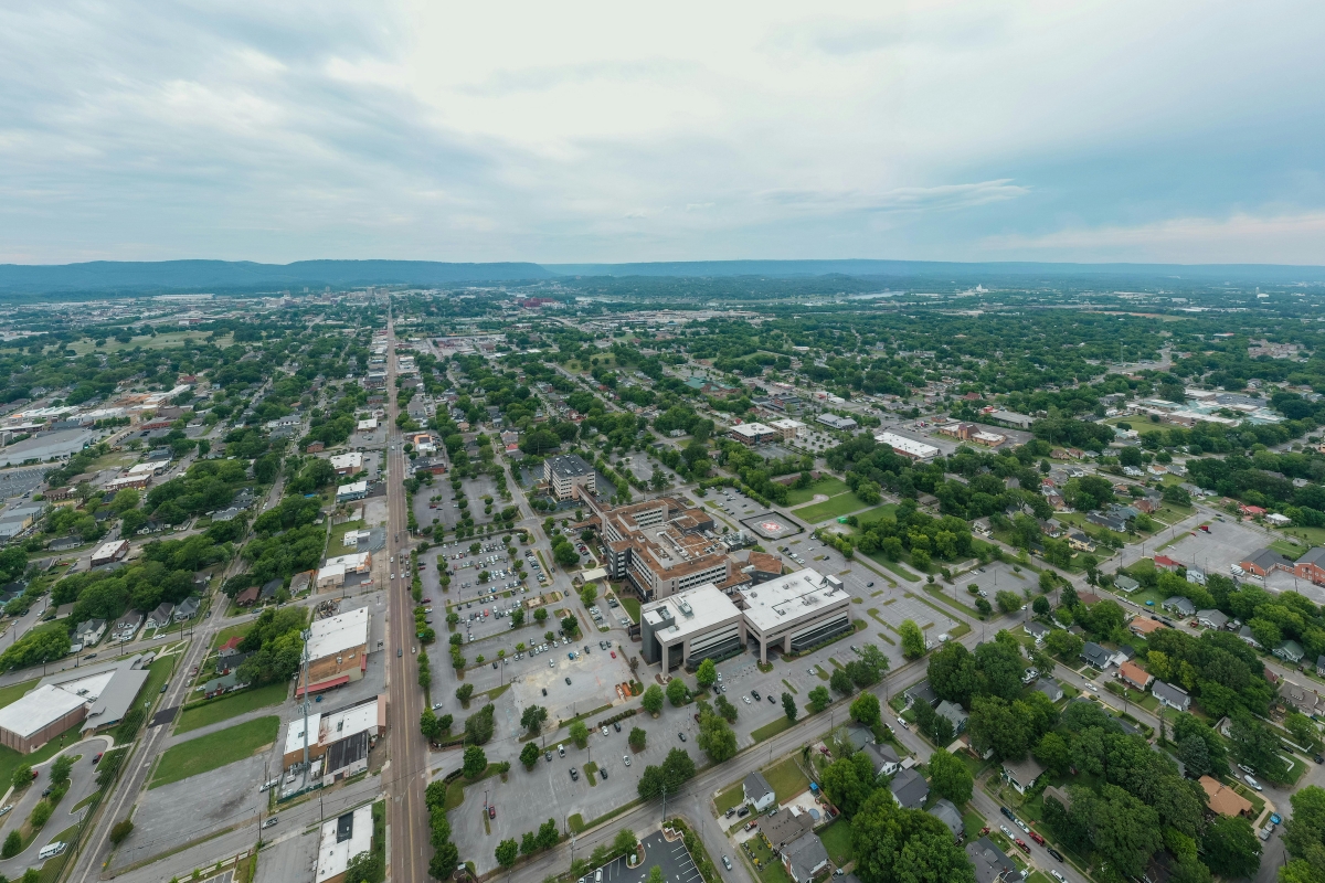 Aerial view of Springdale, Arkansas with residential neighborhoods, commercial buildings, and tree-lined streets under a cloudy sky
