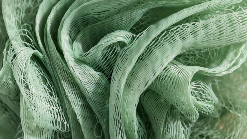 Close-up of flexible green nylon polyamide mesh with overlapping netted strands, showing the material’s fine texture and open structure.