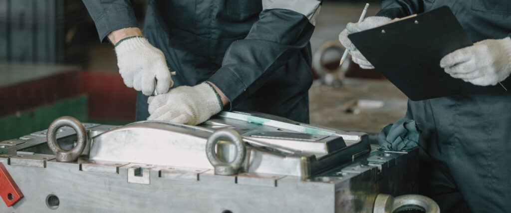 Technicians inspecting metal injection mold tooling during maintenance and quality review