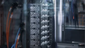 Close-up of an injection mold producing multiple small white plastic components inside a molding press.