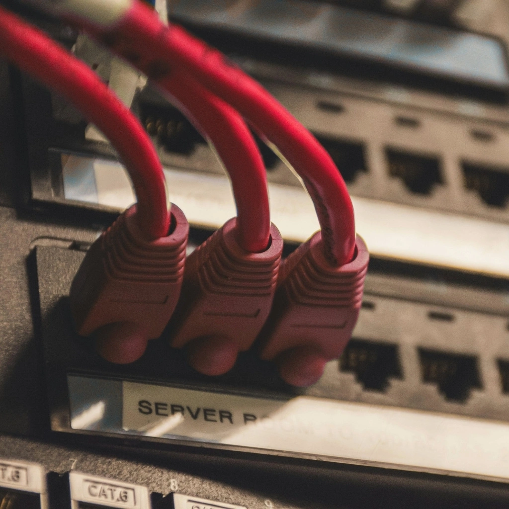 Red Ethernet cables plugged into a server rack network switch with multiple open ports.