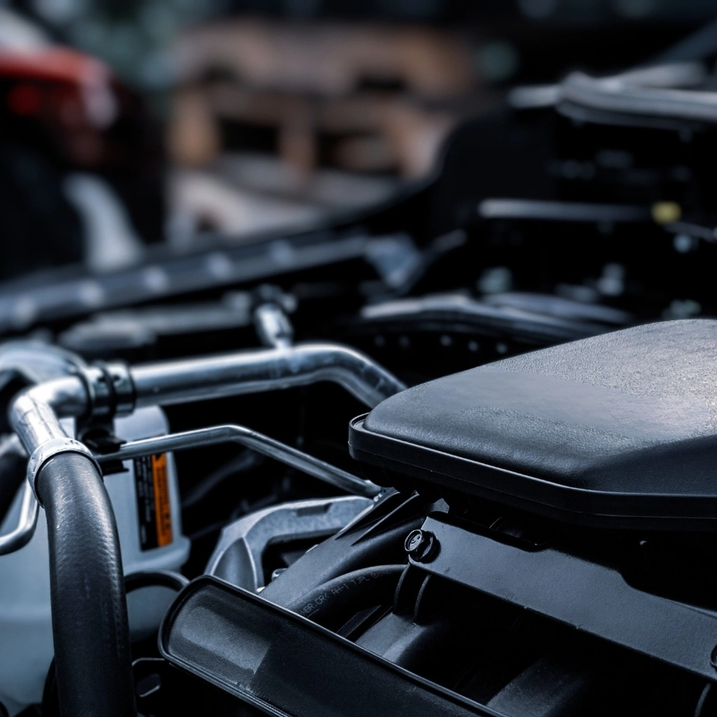Automotive engine compartment with molded plastic covers, battery housing, hoses, and fluid reservoir components