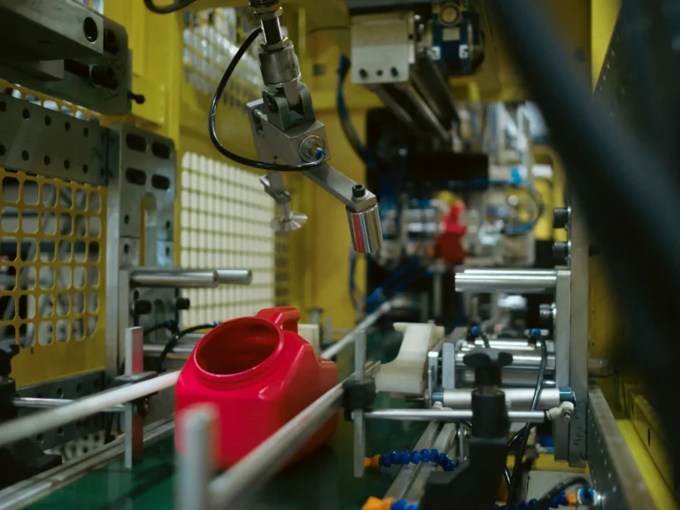 Blow molding equipment producing a red plastic container in a manufacturing facility