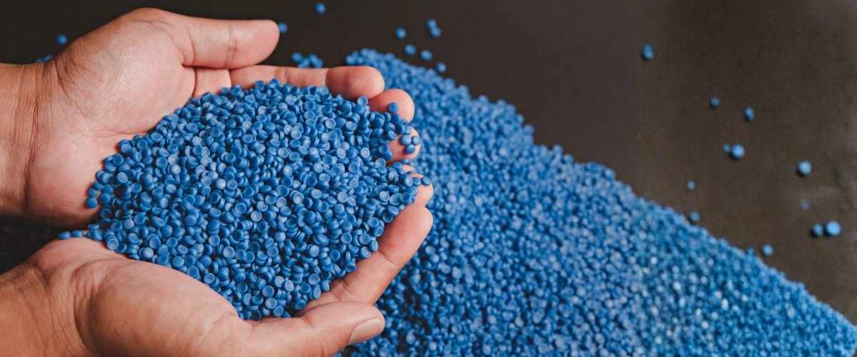 Blue plastic resin pellets being inspected before injection molding