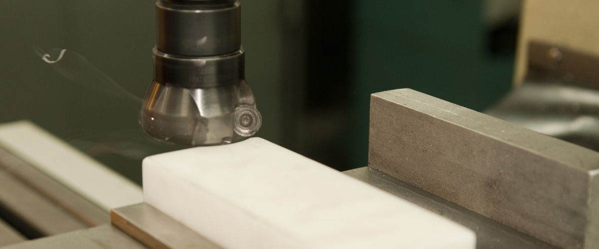 Precision machining of a white Delrin acetal plastic block